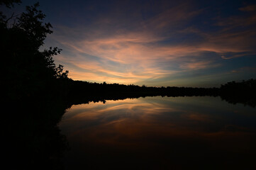 Brilliant colorful clouds in twilight reflected on calm water of Eco Pond in Everglades National Park, Florida on summer evening.