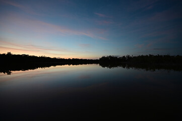 Brilliant colorful clouds in twilight reflected on calm water of Eco Pond in Everglades National Park, Florida on summer evening.