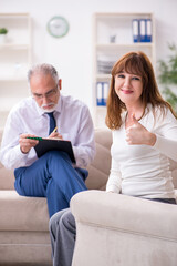 Obraz premium Young woman visiting old male doctor psychologist