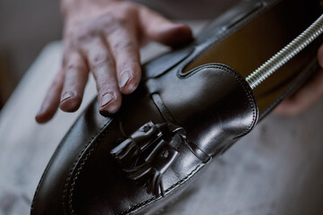 Young caucasian man repairing old male leather shoes. - obrazy, fototapety, plakaty