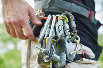 Young Caucasian man doing slackline in the forest at sunset. Close-up on carbines.