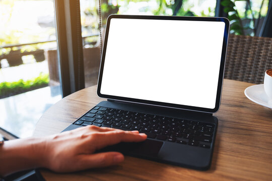 Mockup image of a woman touching on tablet touchpad with blank white desktop screen as a computer pc with coffee cup on the table