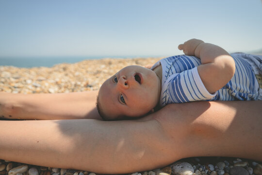 Little baby resting on his mothers legs at the beach