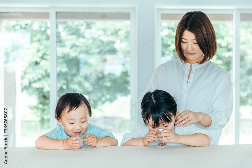 Wall mural 爽やかな白いリビングで楽しそうに水を飲む子どもと母親　kids water family