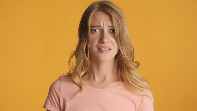 Young frustrated blond woman pinching nose due to bad disgusting smell over colorful background. Awful expression