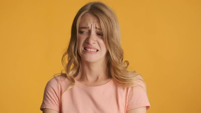 Attractive blond girl feeling aversion frowning face on camera over colorful background. Awful expression