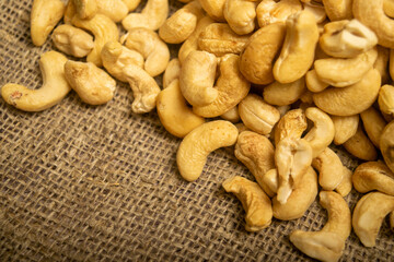 A pile of cashew nuts on burlap with a rough texture surface texture. Close up.