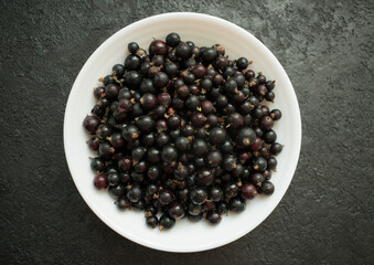 
Blueberries in a white plate on a black background. Top view.