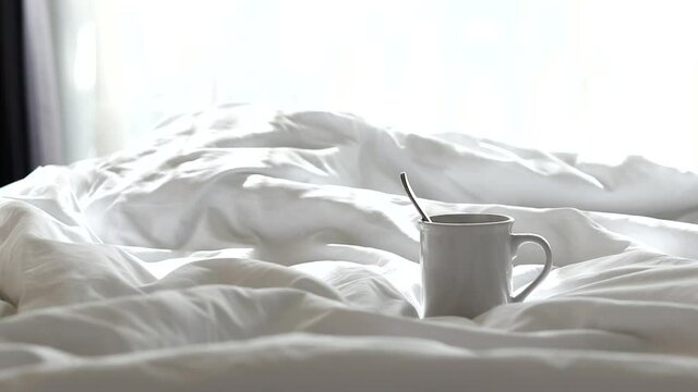 White coffee mugs and smoke rising from the mugs lay on the bed with the morning sunshine.