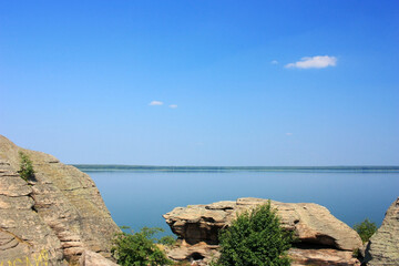 Stone granite rocks on the shore of a blue lake