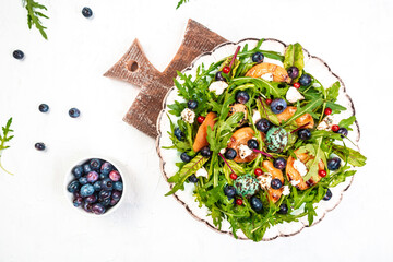 apricot, nectarines, peaches with arugula, berries, goat cheese salad on plate, menu recipe place for text, top view