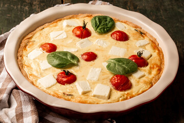 Chicken, spinach and tomatoes pie quiche on a wooden background. Food recipe background. Close up. Top view
