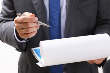 Hand of businessman in suit filling and signing with silver pen partnership agreement form clipped to pad closeup. Management training course, some important document, team leader ambition concept