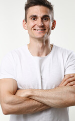 Fitness man portrait cute in a white tank top on a gray background smiling and looking at the camera fashion industry model