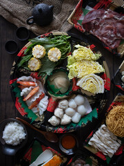 Cooking Chinese Hot Pot at Home. Japanese shabu-shabu flatlay on wooden table. Chicken Broth Hot Pot. Chinese New Year Reunion Dinner.