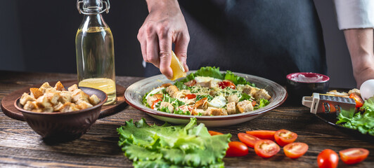 Chef is squeezing out a lemon for salad dressing. Concept of cooking process a delicious fresh dish