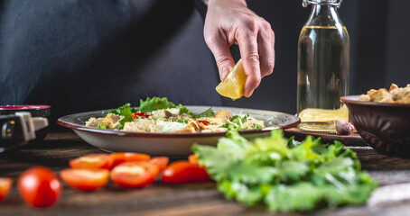 Chef is squeezing out a lemon for salad dressing. Concept of cooking process a delicious fresh dish