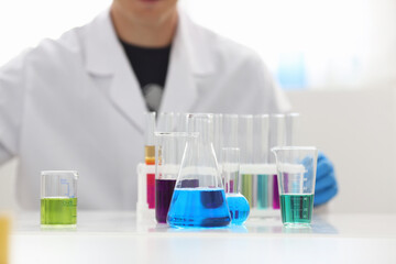 A male chemist holds test tube of glass in his hand overflows a liquid solution of potassium permanganate conducts an analysis reaction takes various versions of reagents using chemical manufacturing