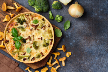 Homemade lorraine quiche or pie with chicken, broccoli and chanterelles on a blue background. Tart with meat and mushrooms. Top view. Copy space
