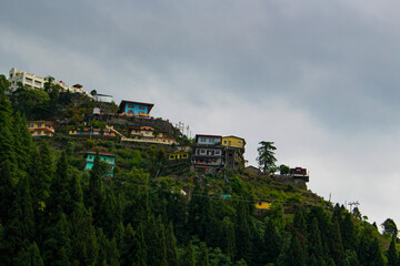 Fototapeta na wymiar Landscape with colorful buildings built on the slop of mountain between the trees.