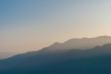The dark silhouettes of the mountains covered by the fog at dawn.