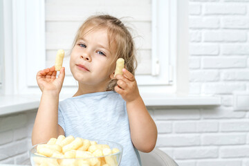 child eating corn sticks at the kitchen table with appetite