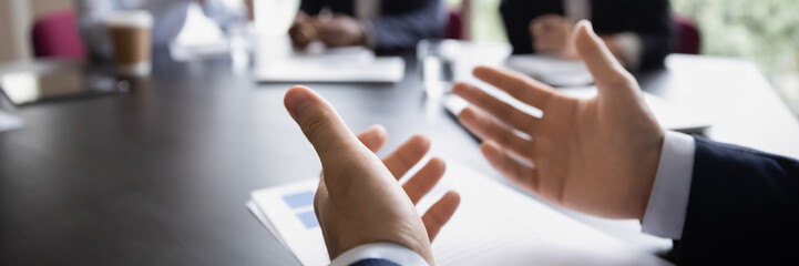 Businessman project leader gesticulate hands while talking during formal group meeting, close up. Convincing speech of speaker. Negotiations concept. Horizontal photo banner for website header design