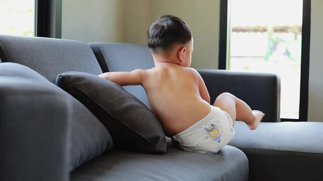 Cute Asian baby boy climbing the sofa