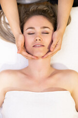 Fototapeta na wymiar Young blond woman receiving a head massage in a spa center.