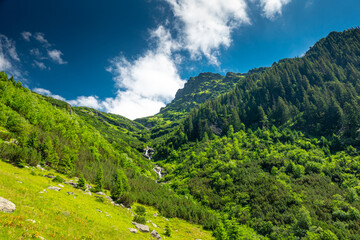 Fototapeta na wymiar Amazing river waterfall in the heart of the mountains during a sunny day - Romania Fagaras Mountains