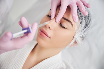 Obraz na płótnie Canvas Calm female patient undergoing injectable beauty procedure