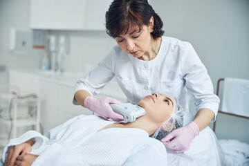Obraz na płótnie Canvas Qualified medical specialist enhancing woman face skin