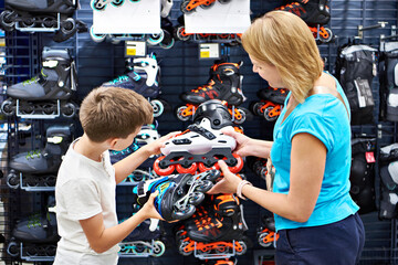 Boy and mother choosing roller skates at sport store