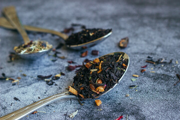 Fototapeta na wymiar Various types of herbal tea in spoons. Spoons with dry tea leaves. Tea on a concrete background