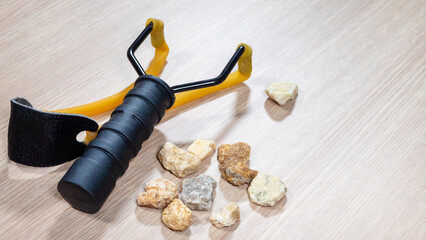 Man hand take stone with slingshot small hand-powered projectile weapon on wooden background....