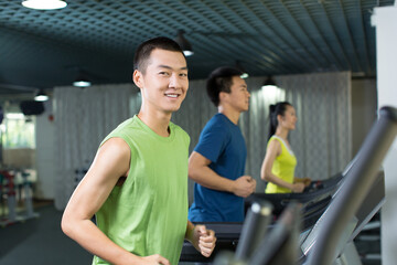 Fototapeta na wymiar Young people running on treadmill in the gym