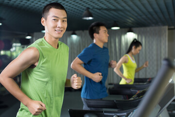 Fototapeta na wymiar Young people running on treadmill in the gym