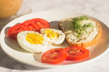 Delicious breakfast on the table. Boiled eggs, tomatoes, cream cheese sandwich, dill on a plate