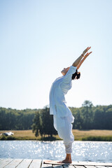 a young girl does yoga on a lake on a Sunny summer day, meditation, relaxing pose, solitude in nature, peace, relaxation, asana, healthy lifestyle, life style, Zen