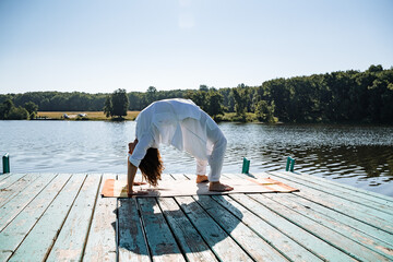 a young girl does yoga on a lake on a Sunny summer day, meditation, relaxing pose, solitude in nature, peace, relaxation, asana, healthy lifestyle, life style, Zen