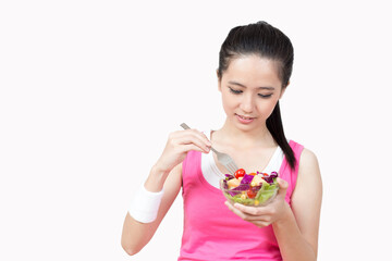 Young Asian woman eating salad after exercise in the gym