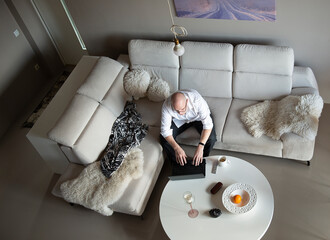 mature man using laptop on sofa at home during quarantine of coronavirus covid-19