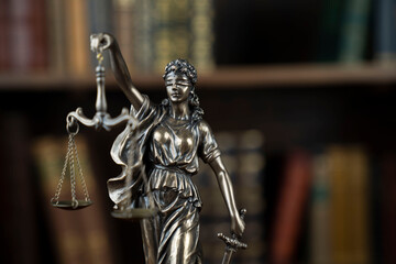 Law theme. Judge chamber. Themis statue on brown shining desk. Collection of legal books in the...