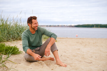 lässiger Mann sitzt am See und lächelt