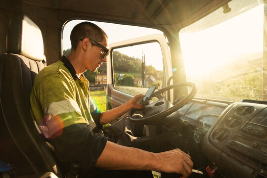 Young truck driver checking the smartphone at work