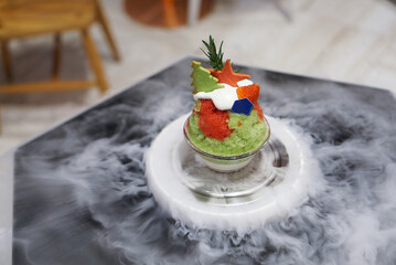 Christmas kakigori, matcha and strawberry granita topped with red and green cookies served with dry ice. top view.