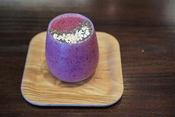 Purple Smoothies. A cup of blended mix berry and beetroot topped with chia seed and oats on wooden...