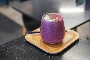 Purple Smoothies. A cup of blended mix berry and beetroot topped with chia seed and oats on wooden...