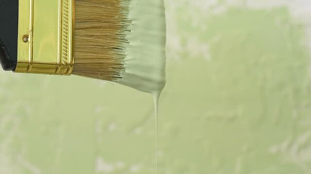 Thick green colour paint drop falls slowly freshly painted surface background. Slow motion artistic footage, paint pours from wide brush paper, plate, or table. Art house industrial decor concept
