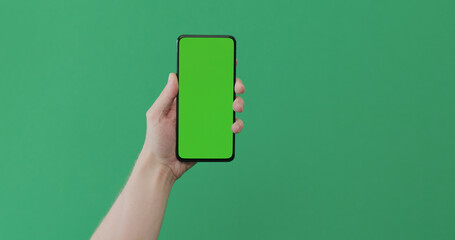 Young man hand hold smartphone with green screen on green background